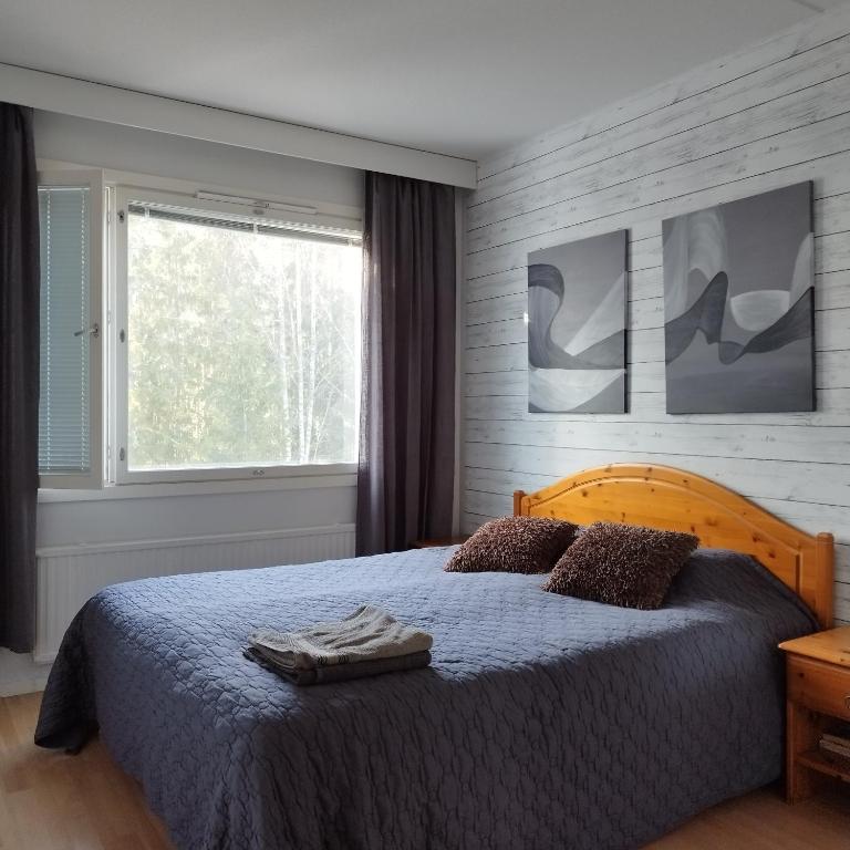 a bedroom with a bed with a blue blanket and a window at Scandinavian taiteilijan 3h huoneisto in Lahti