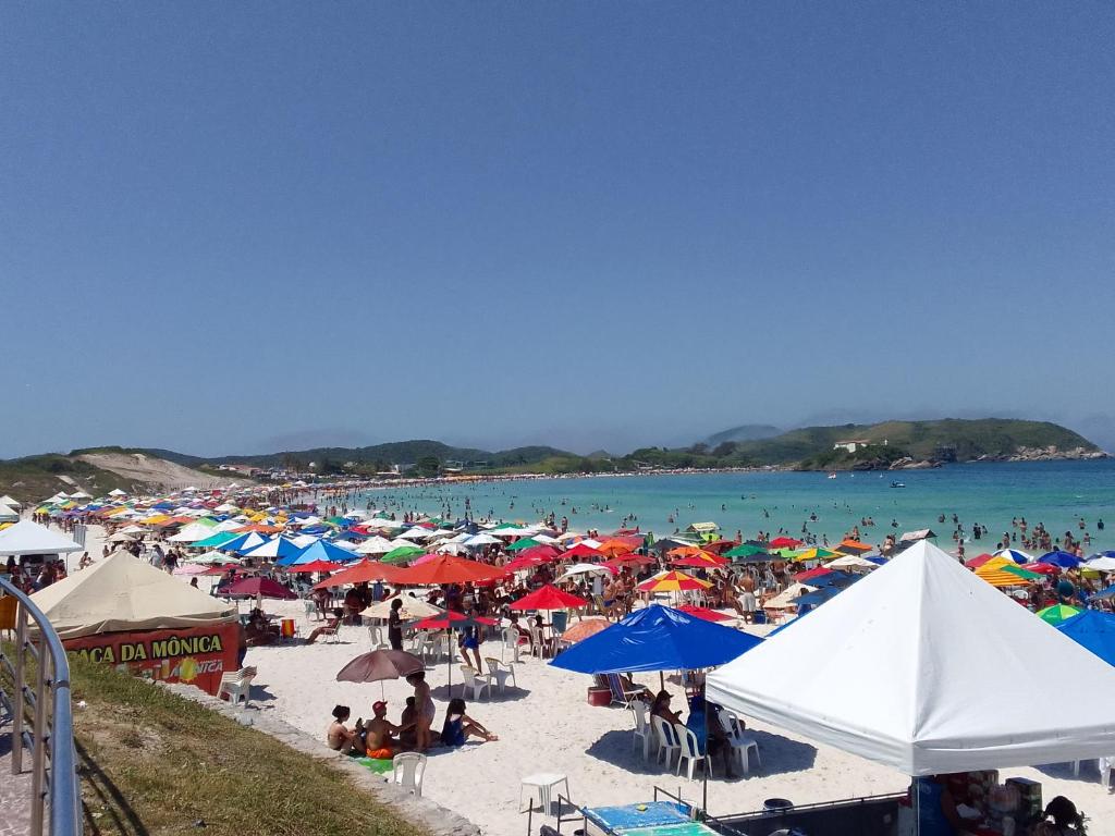 uma multidão de pessoas numa praia com guarda-sóis em APT Praia Forte Passagem em Cabo Frio