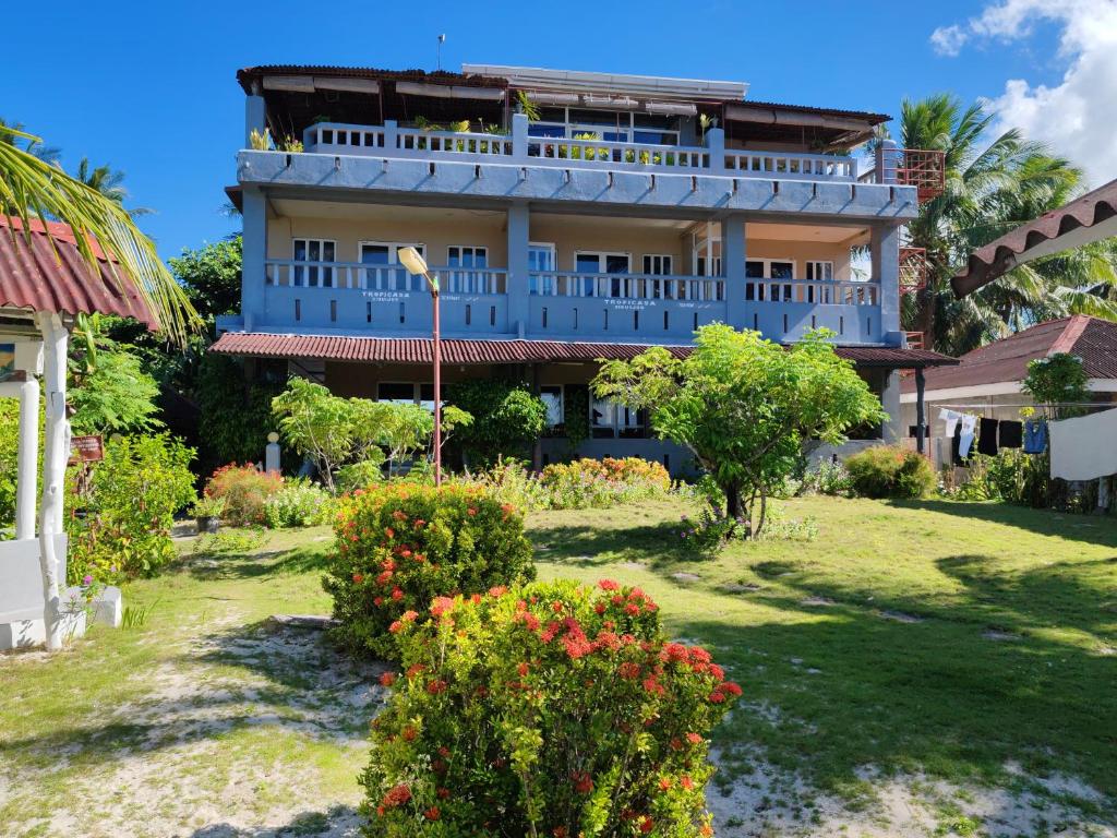ein großes blaues Gebäude mit Blumen im Hof in der Unterkunft Tropicasa Siquijor Seafront Guest House in Solangon