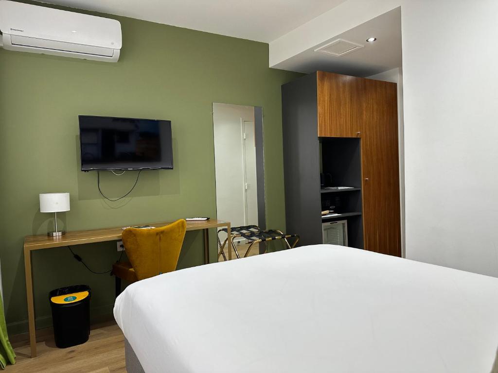 a bedroom with a bed and a desk and a tv at Hôtel Exsel Créolia in Saint-Denis