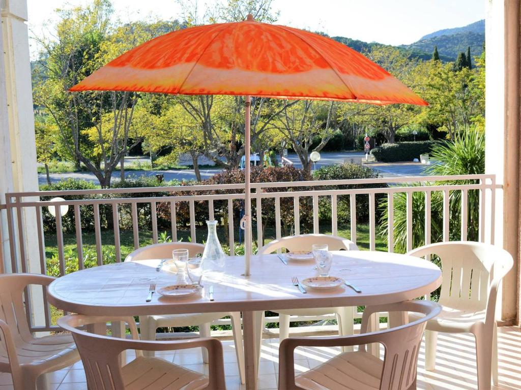 - une table blanche avec un parasol orange sur une terrasse couverte dans l'établissement Appartement 2 pièces, terrasse, parking privé, proche plage, 6 couchages - Le Lavandou - FR-1-251-547, au Lavandou