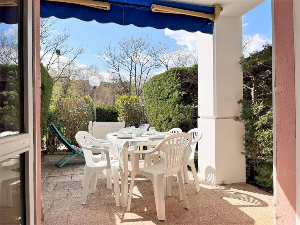 une table blanche et des chaises sur une terrasse dans l'établissement Appartement T2 Cabine, 6 Couchages, Terrasse Ouest, 100m Plage et Commerces, Parking Privatif - FR-1-251-530, au Lavandou