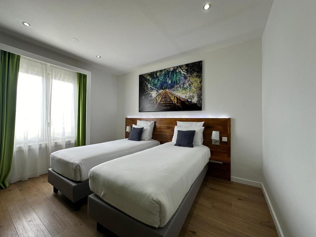 a hotel room with two beds and a painting on the wall at Hôtel Exsel Créolia in Saint-Denis