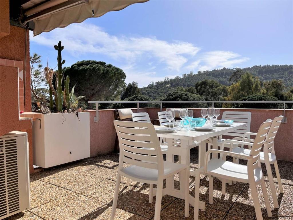 d'une table à manger blanche et de chaises sur un balcon. dans l'établissement Appartement Vacances - 4 Pers, Piscine, Terrasse, Proche Plage au Lavandou - FR-1-251-556, au Lavandou