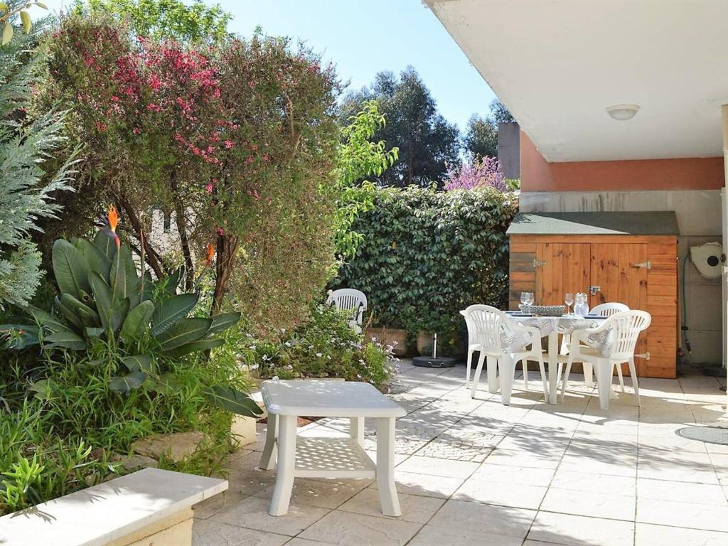 - une terrasse avec une table, des chaises et des fleurs dans l'établissement Appartement Climatisé 4 Pièces avec Jardin, à 200m de la Plage - Le Lavandou, Cavalière - FR-1-251-568, au Lavandou
