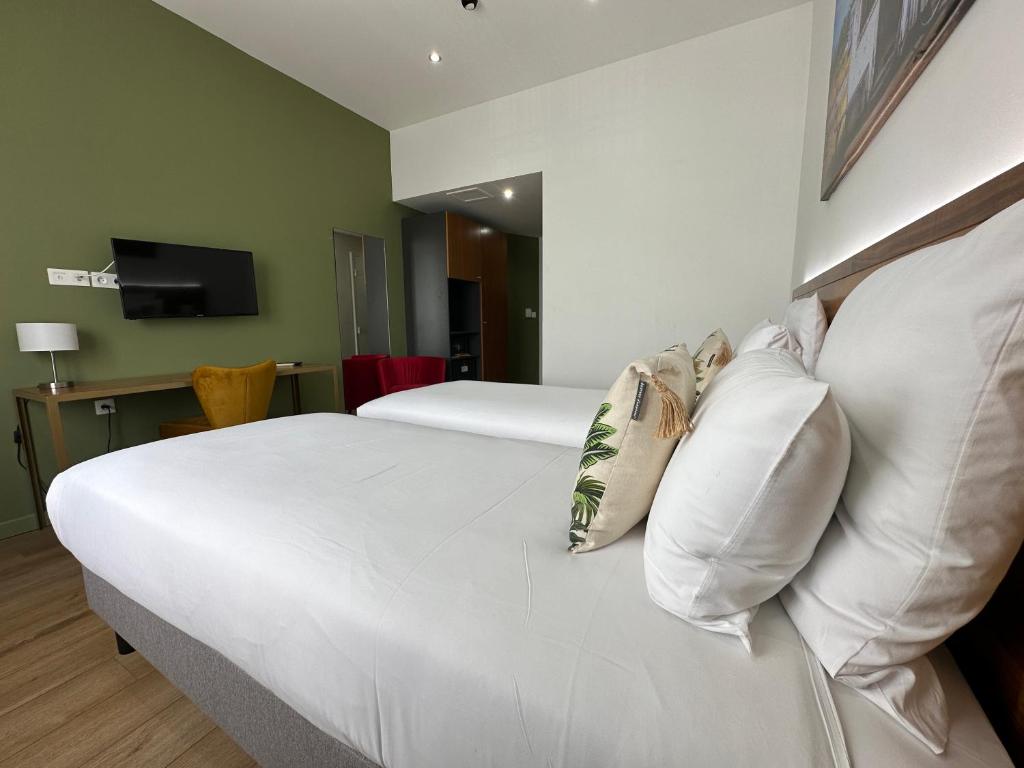 a bedroom with a white bed with pillows at Hôtel Exsel Créolia in Saint-Denis