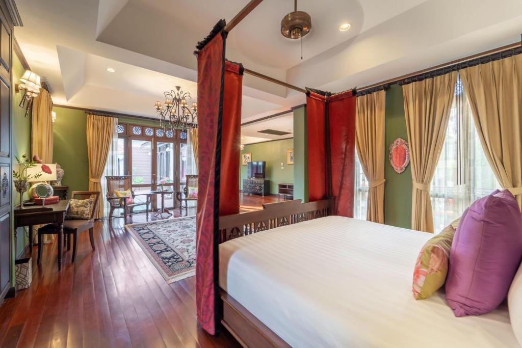 A canopy-bed room with a separate table-and-chairs area by tall windows.