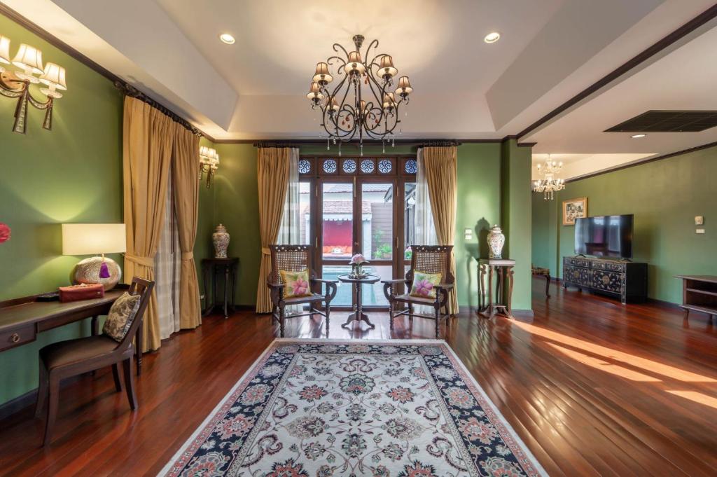A formal hotel sitting room with green walls, traditional furnishings, and a television.
