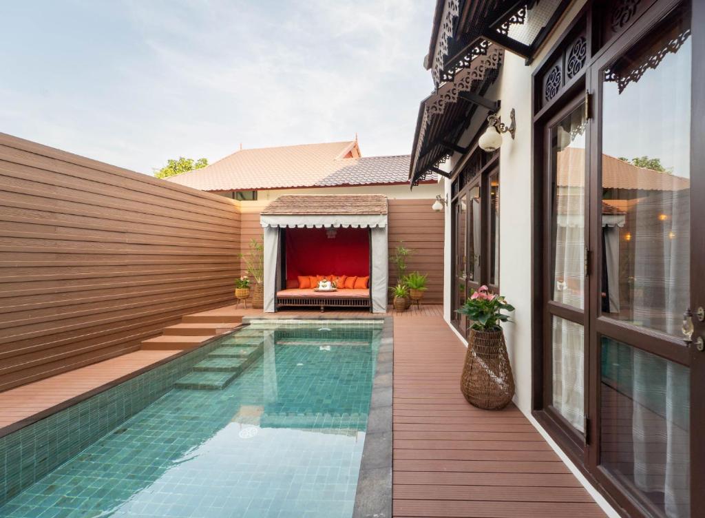 A narrow private-looking pool beside a timber deck and covered daybed.