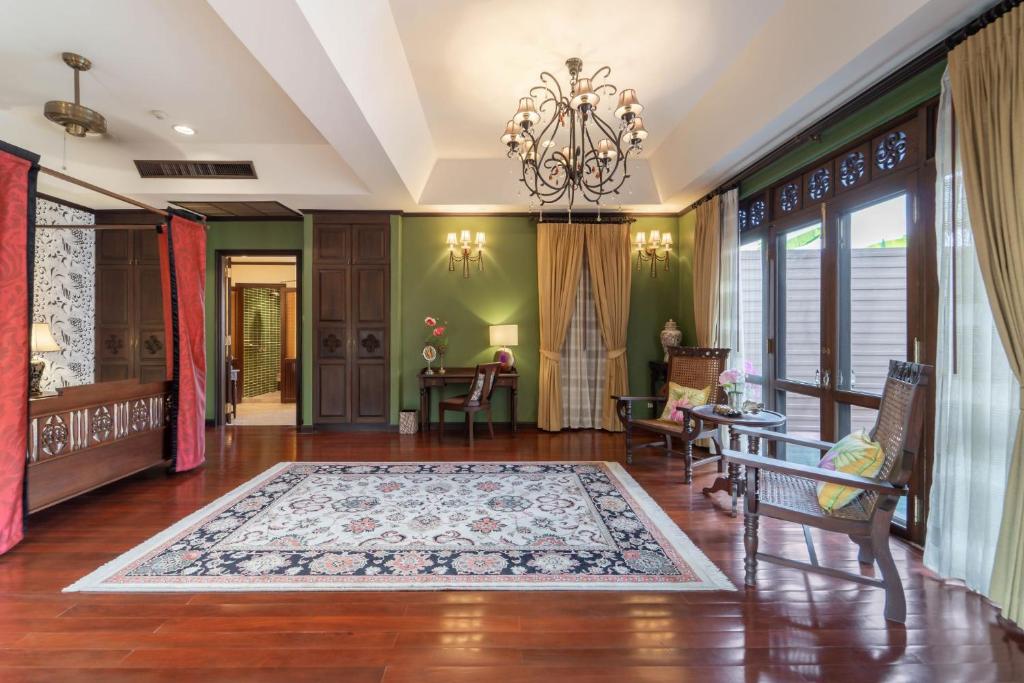 A spacious traditional-style lounge with green walls, a chandelier and garden-facing windows.