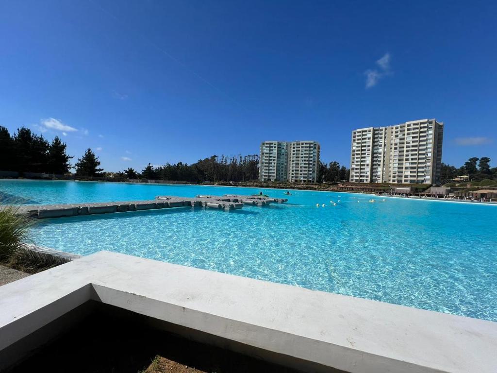 a large pool of blue water with buildings in the background at Departamento Lagunamar con patio privado in Las Cruces