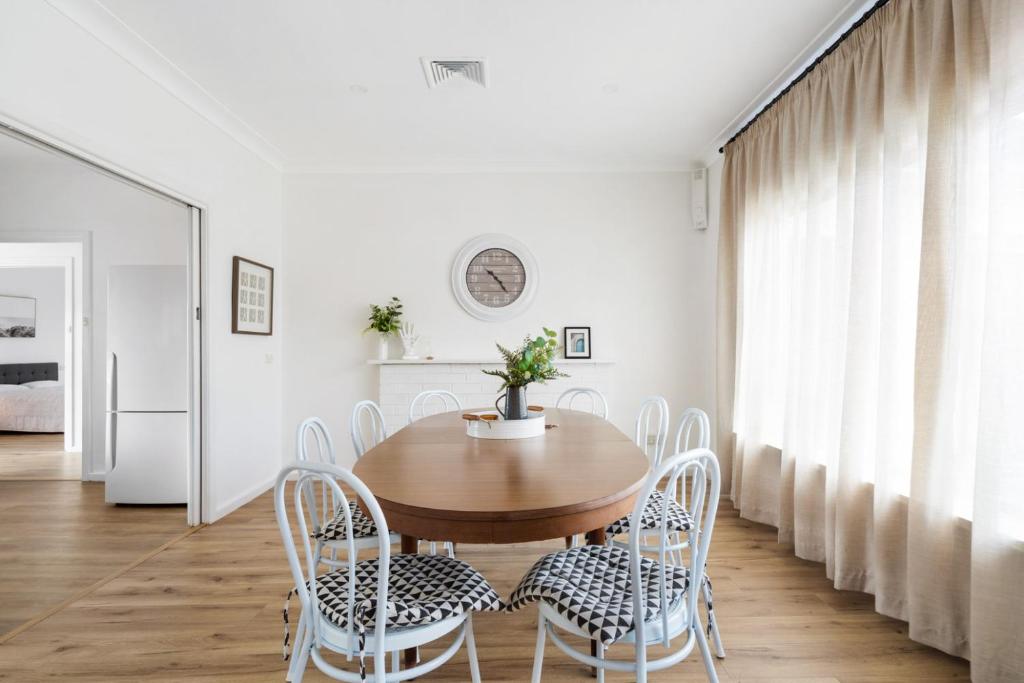 comedor con mesa de madera y sillas blancas en Space and Comfort on Marshall, en Lavington