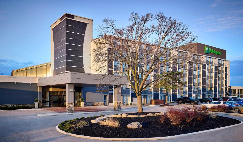 ein Hotelgebäude mit einem Baum davor in der Unterkunft Holiday Inn Burlington Hotel & Conference Centre, an IHG Hotel in Burlington