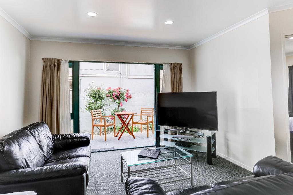 uma sala de estar com um sofá e uma televisão de ecrã plano em ASURE Cooks Gardens Motor Lodge em Whanganui