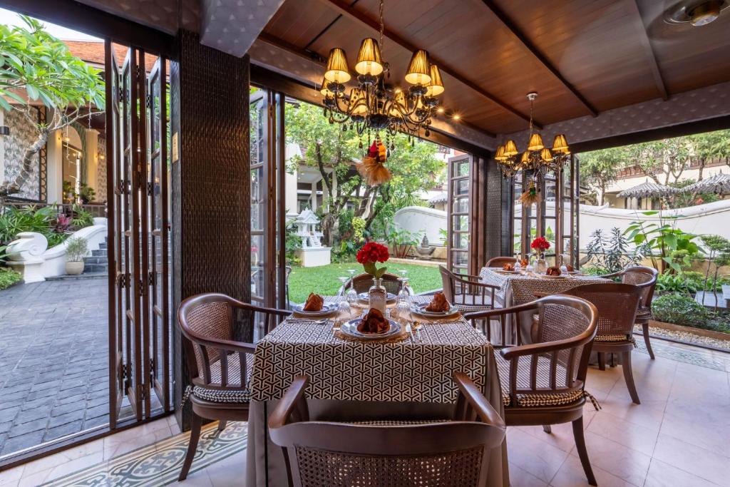 A garden-level dining area with open doors, set tables and a shaded traditional interior.