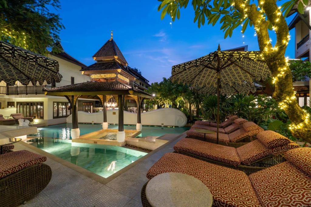 An atmospheric evening view of the illuminated pool courtyard and covered loungers.