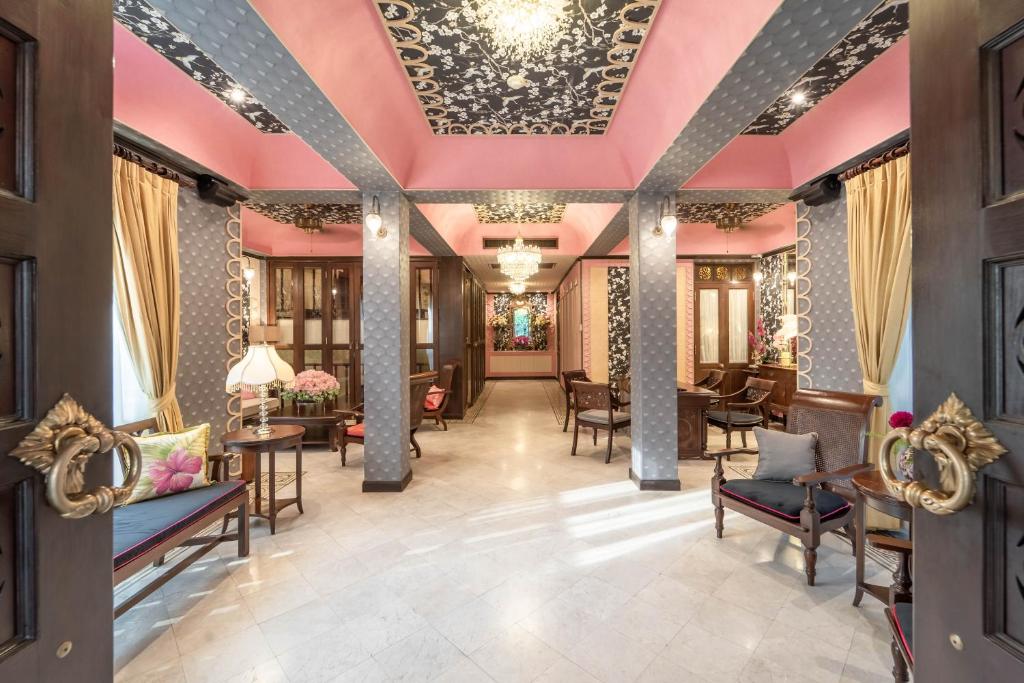 A richly decorated lobby lounge with pink ceilings, carved woodwork and small seating areas.