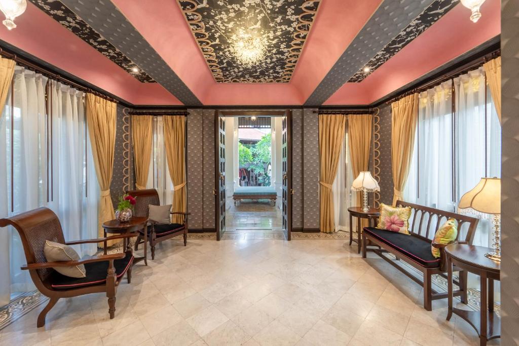 An ornate lounge with patterned ceiling panels, seating and an open garden-facing doorway.