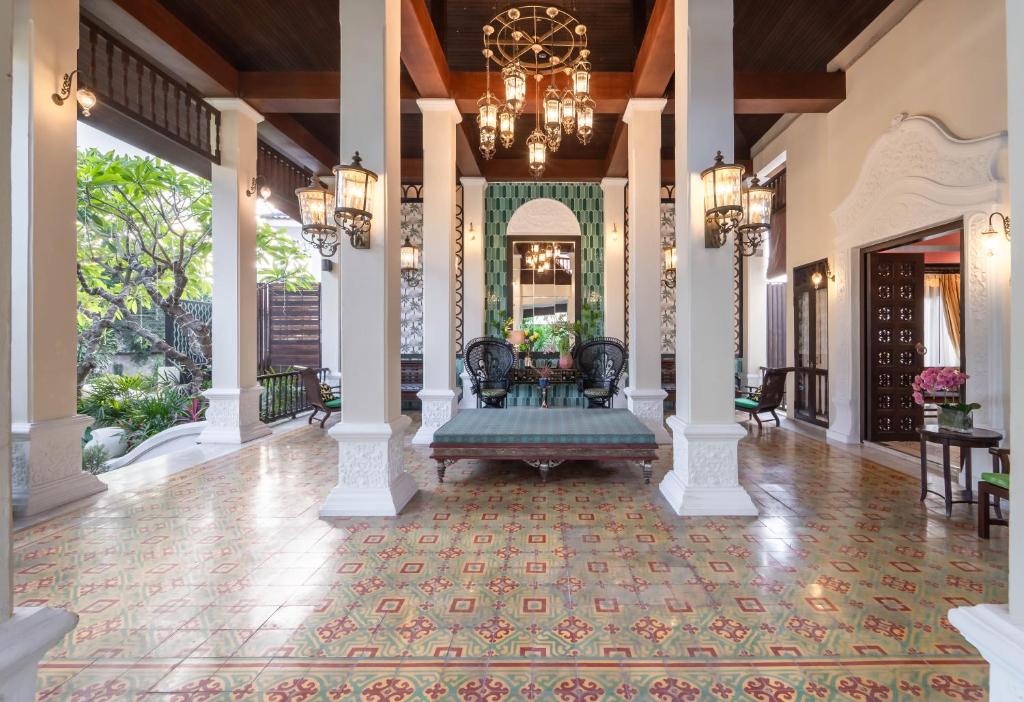 A bright open lobby with patterned tile flooring, carved columns and hanging lanterns.