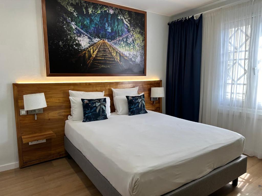 a bedroom with a large white bed with blue pillows at Hôtel Exsel Créolia in Saint-Denis