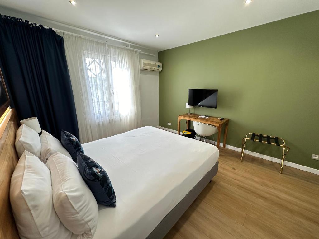 a bedroom with a bed and a desk with a television at Hôtel Exsel Créolia in Saint-Denis
