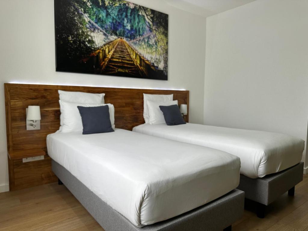 two beds in a hotel room with a painting on the wall at Hôtel Exsel Créolia in Saint-Denis