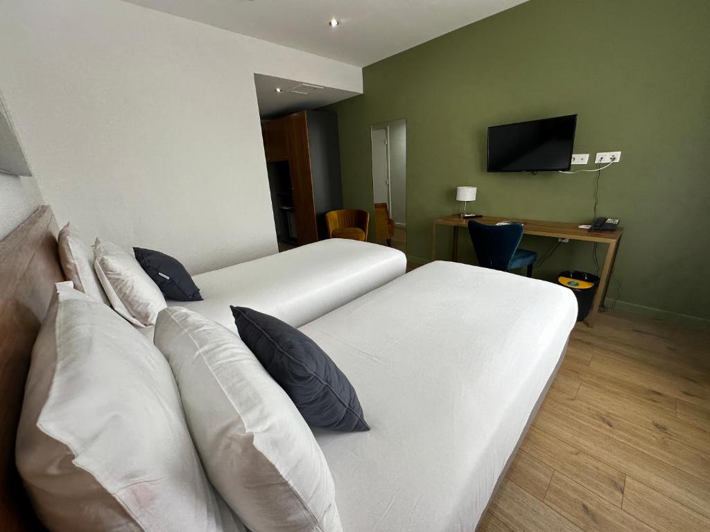 a hotel room with two white beds with pillows at Hôtel Exsel Créolia in Saint-Denis