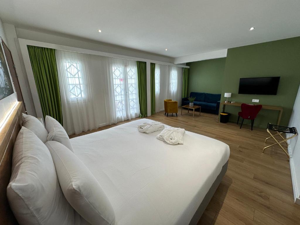 a bedroom with a white bed and a living room at Hôtel Exsel Créolia in Saint-Denis