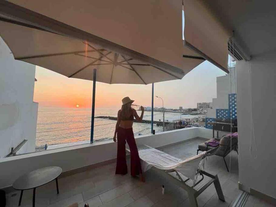 a woman standing on a balcony with an umbrella at La mejor Vista al Point de la Playa San Bartolo in San Bartolo