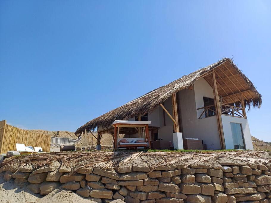 una casa con techo de paja sobre una pared de piedra en Casa Yemaya, Vichayito, en Vichayito