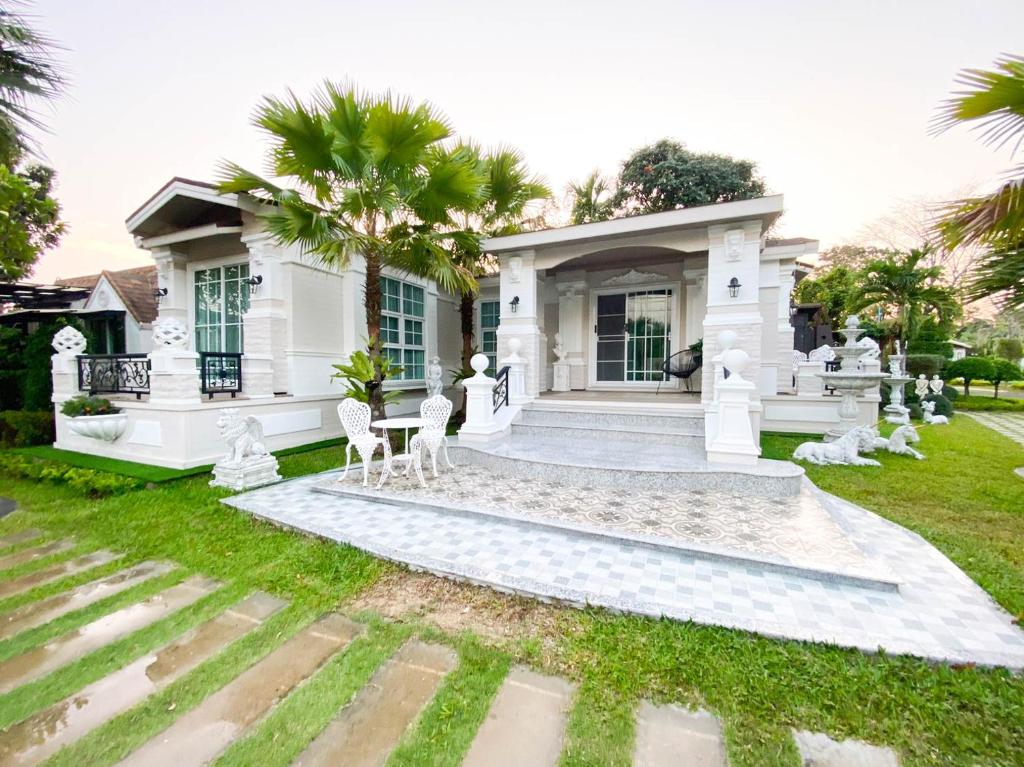 ein weißes Haus mit Stühlen im Hof in der Unterkunft Baan Nimit Resort 