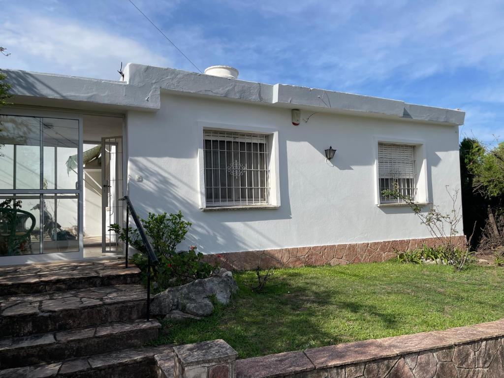 a white house with a porch and windows at Casa Rosa in Alta Gracia