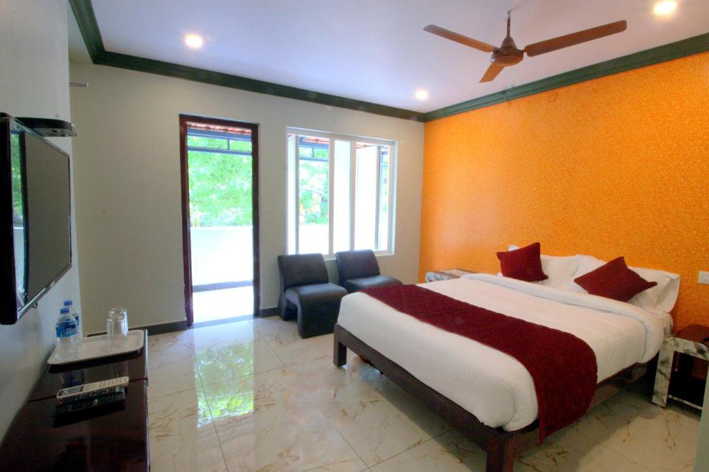 a bedroom with a bed and a couch and a tv at Serenity Sands Beach Resort in Pondicherry