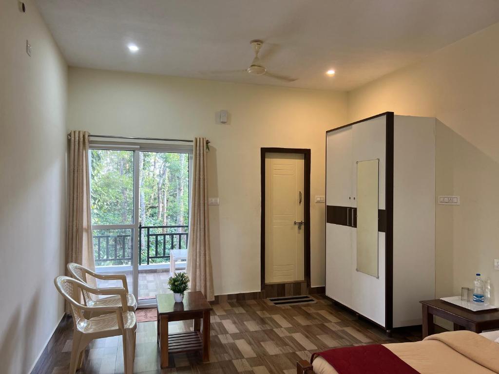 a living room with a bed and a large window at Sri Lakshmi Estates in Siddapur