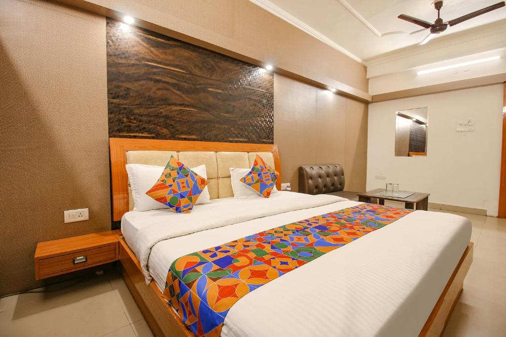 a bedroom with a large bed with a colorful blanket at FabHotel Neena Palace in Bhopal