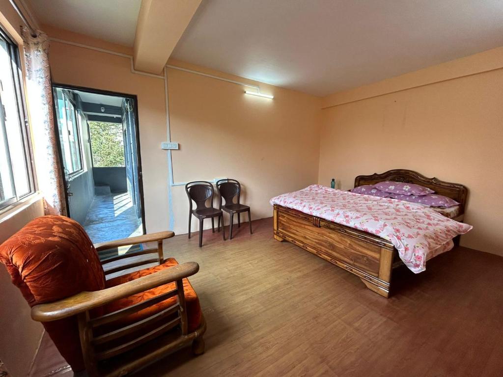 a bedroom with a bed and two chairs and a window at Deepjen Homestay in Darjeeling