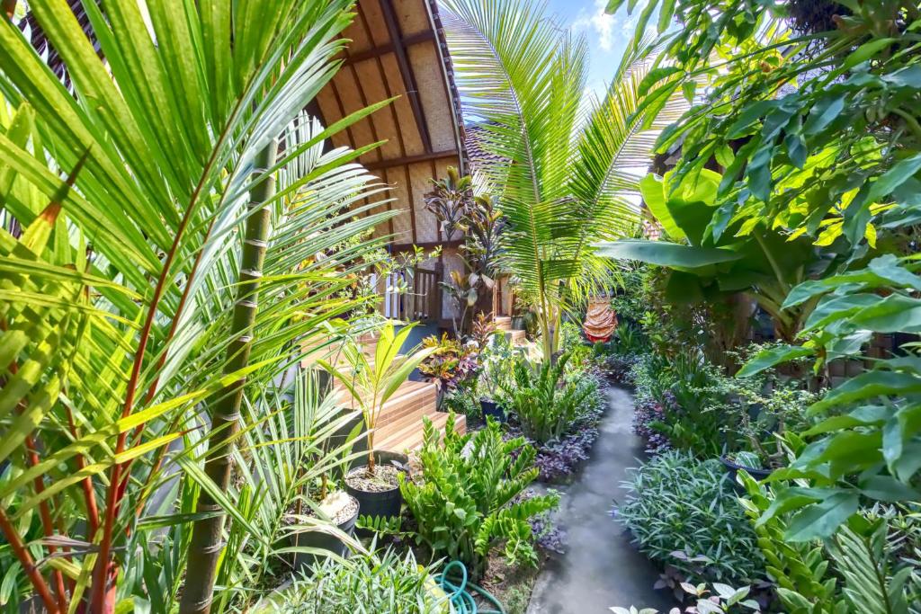 a garden with palm trees and plants at The Catar Cottages in Nusa Penida