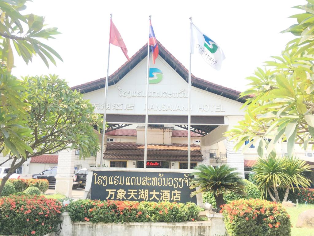 um sinal em frente a um edifício com bandeiras em Dansavanh Vientiane Hotel em Vientiane