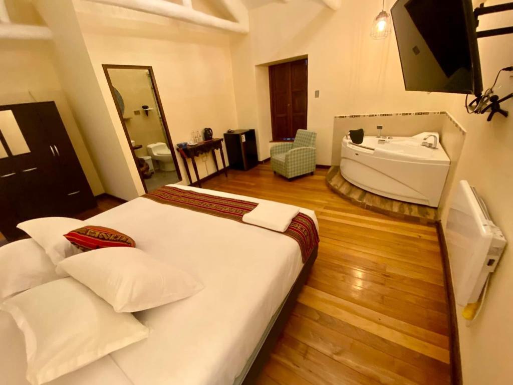 a bedroom with a large bed and a bath tub at Cusco Hotel Boutique in Cusco