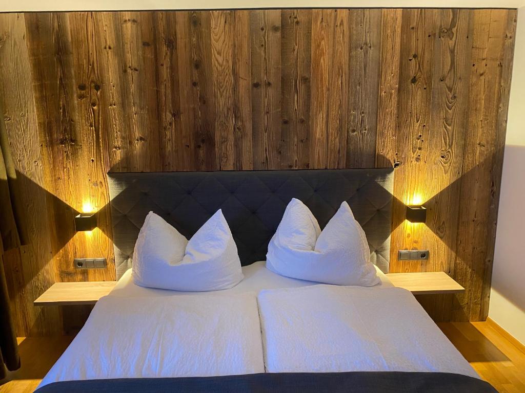 a bed with white pillows and a wooden wall at Ferienhaus Edith in Kaltenbach