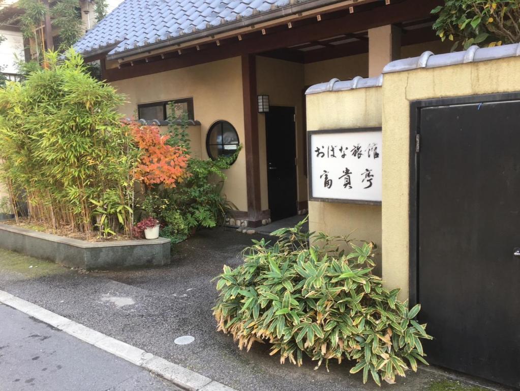 un edificio con una puerta y plantas delante de ella en おばな旅館 富貴亭, 
