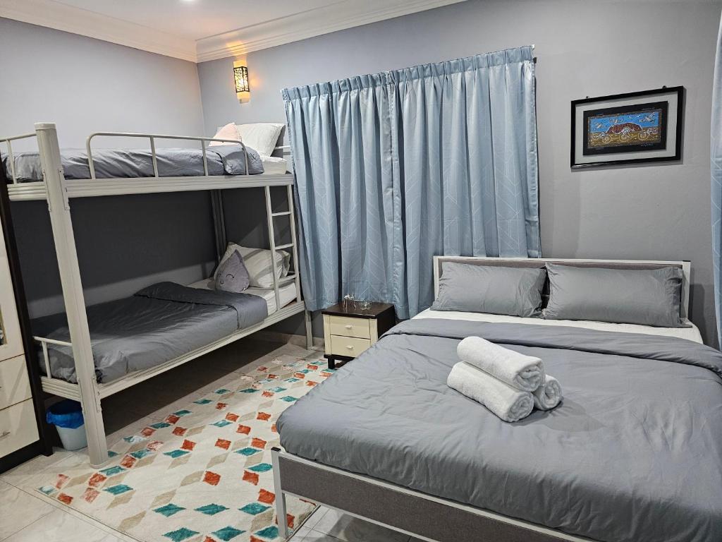 a bedroom with two bunk beds and a bed with towels at Cosy Home + Mini Golf in Kuantan in Kuantan