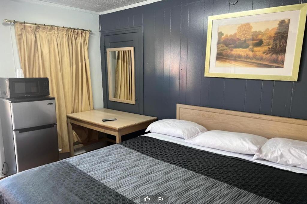 a bedroom with two beds and a desk and a television at Anson Inn By OYO in Anson