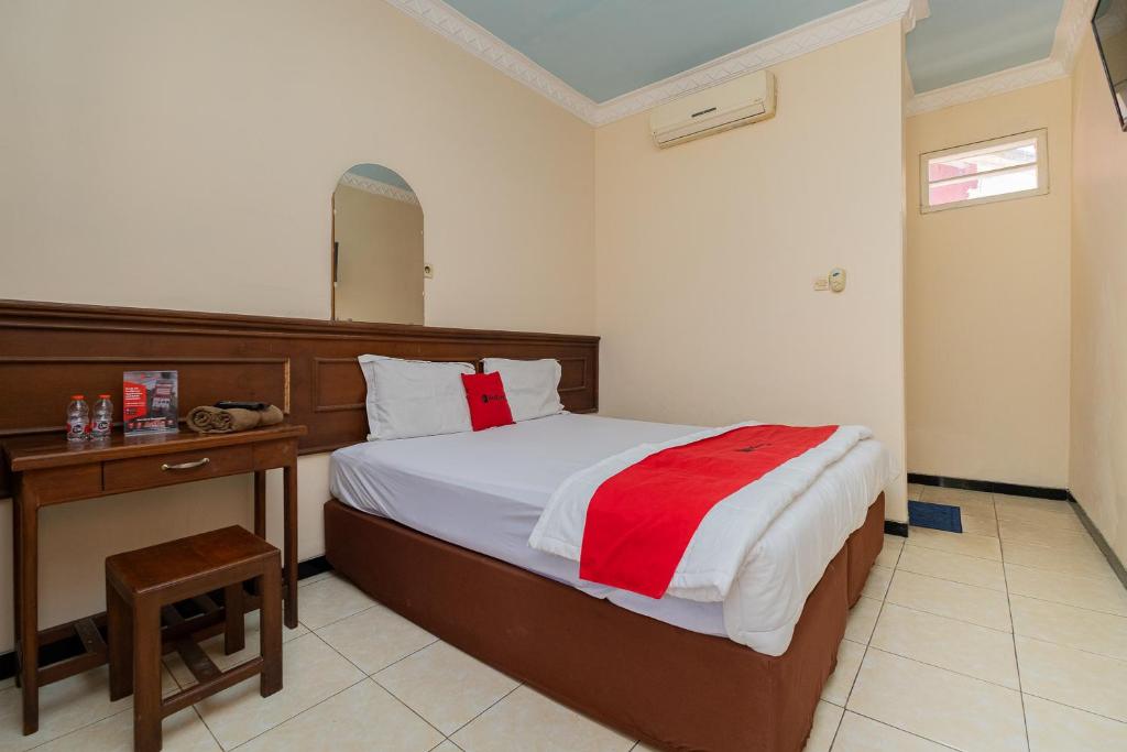 a bedroom with a bed and a table and a mirror at RedDoorz near Bojonegoro Train Station in Bojonegoro