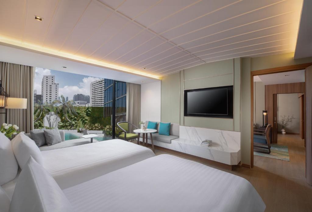 a hotel room with two beds and a flat screen tv at Nysa Hotel Bangkok Sukhumvit 11 in Bangkok