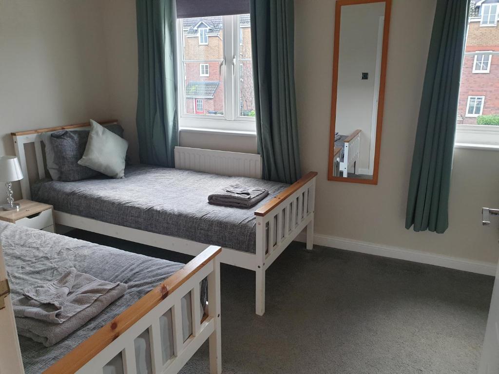 a small bedroom with two beds and a mirror at Oldwood Place Townhouse in Livingston