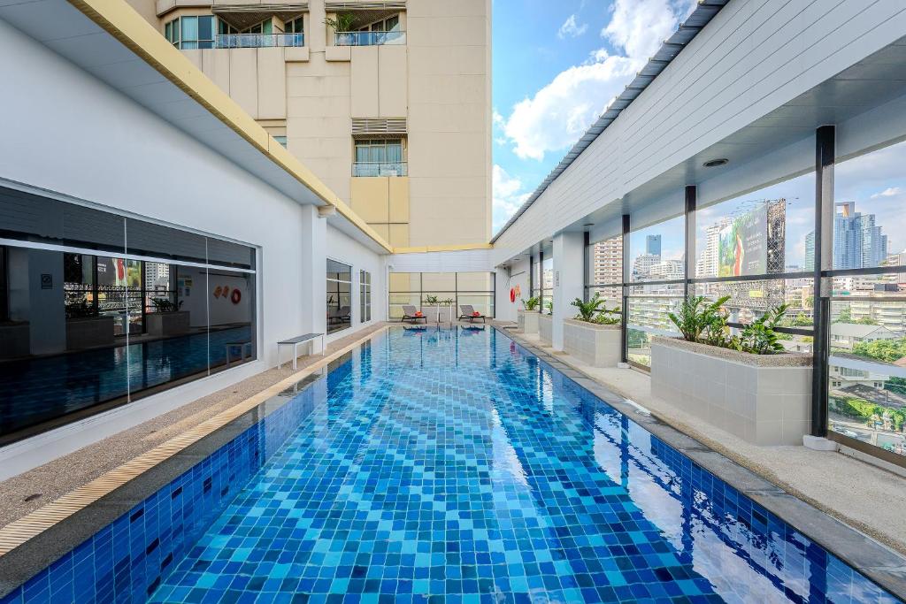 a swimming pool in a building with windows at Citadines Sukhumvit 16 Bangkok in Bangkok