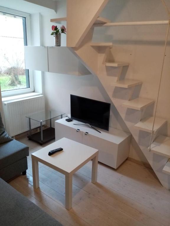 ein Wohnzimmer mit einer Treppe, einem TV und einem Tisch in der Unterkunft Historical Varkor Villa @ Koszeg Castle Wall 2 in Kőszeg