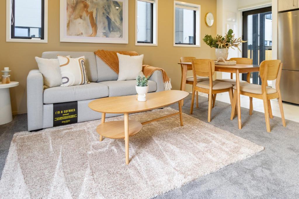Una sala de estar con un sofá, una mesa y sillas. en New Brighton Beach Explore - King Bed and sofa bed, en Christchurch