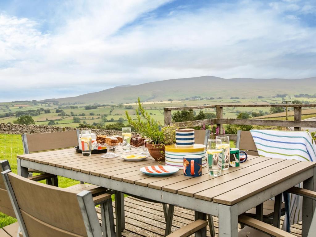 een houten tafel met eten en stoelen op een terras met uitzicht bij 2 Bed in Caldbeck 80563 in Caldbeck